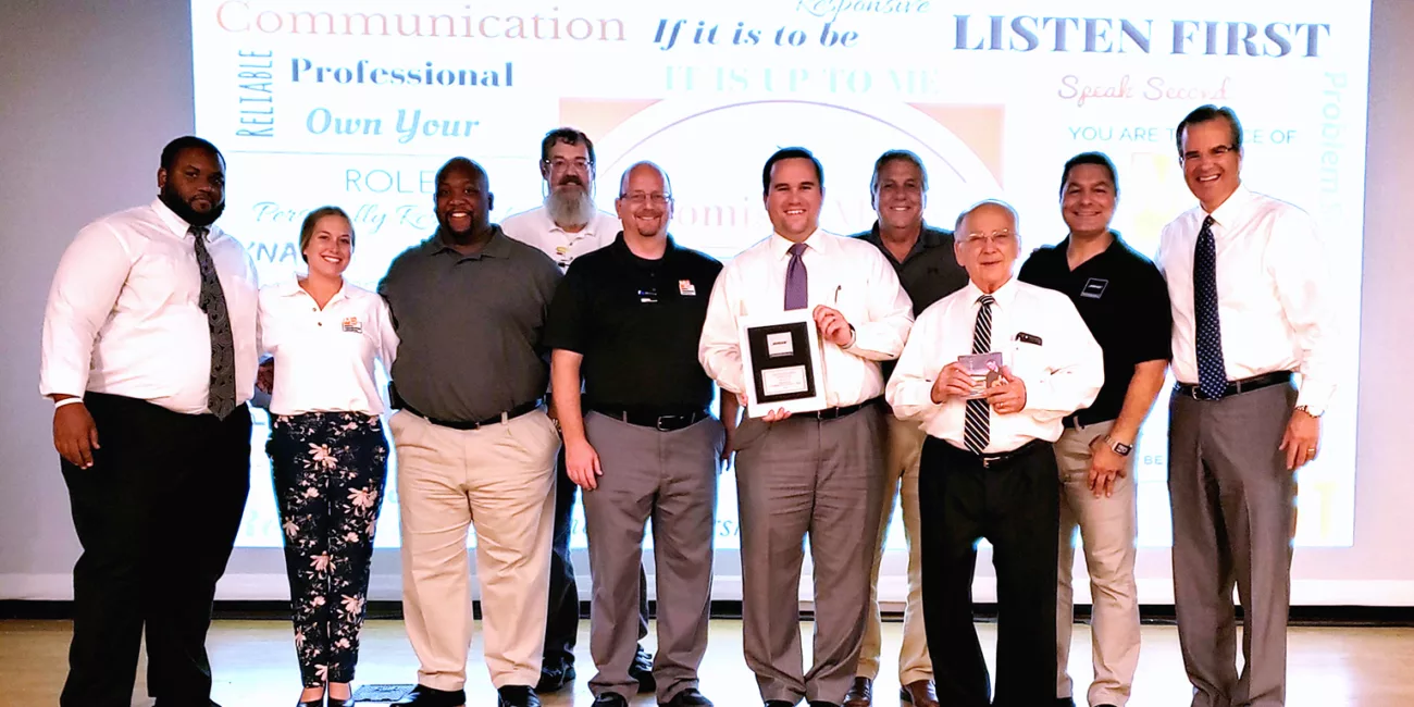 MCC Audio Visual Solutions salespeople displaying the award presented to MCC by Bose