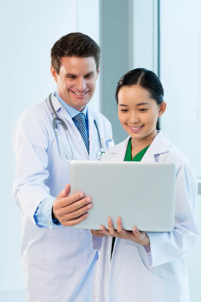 Two medical professionals, one male and one female, looking at a computer screen.