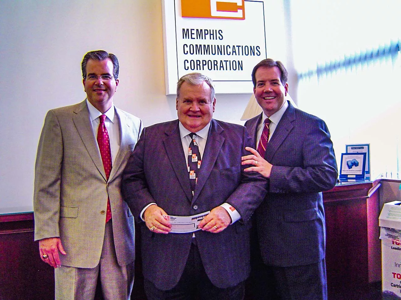 Scot (left) and Shane (right) present Dean (middle) with the first check for the purchase of Memphis Communications Corporation