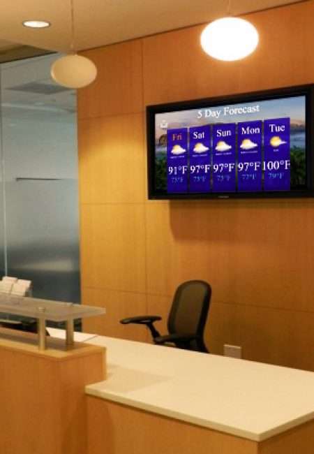 MCC Digital Signage display on a wall behind the reception area of an office.