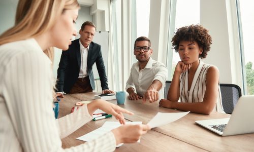 Business meeting. Group of young business people looking at documents and discussing something while