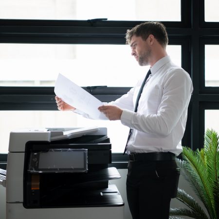 Businessman in office working with copier. Image for Office Equipment/Copiers/Printers pages of the Document Solutions section of the MCC website