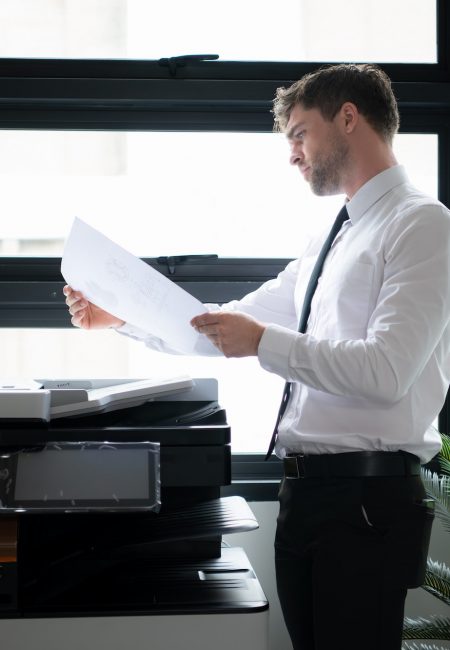 Businessman in office working with copier. Image for Office Equipment/Copiers/Printers pages of the Document Solutions section of the MCC website