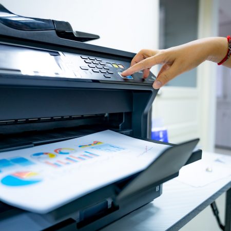 Office worker prints paper on multifunction laser printer. Copy, print, scan, and fax machine. Image for e-faxing/digital fax pages of the Document Solutions section of the MCC website