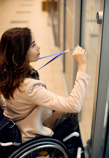 Wheelchair-bound businesswoman accessing her office with smart card.