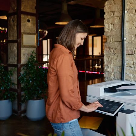 Young woman employee working on printer at coworking office - MCC Office Technology Solutions
