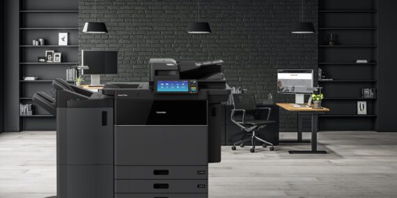 Toshiba eStudio 7516ac copier in an office with black walls and modern desks.
